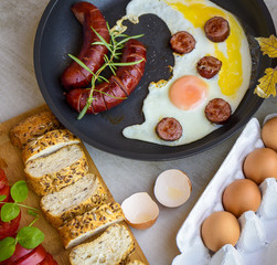 Fried sausages and eggs in a pan served with bread, tomatoes and egg shell, TOP VIEW