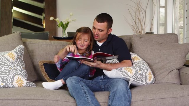 Father reading to daughter on the couch