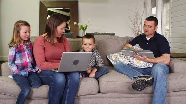 Family using laptop and reading book in living room
