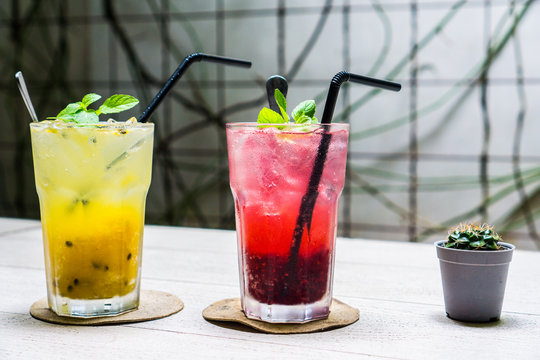 Colorful Sparkling Drink : Passion fruit-Mango Soda and Raspberry Soda to quench your thirst on the wooden table with small Cactus decoration 