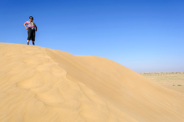 Indian boy, tourist, with binoculars, standing on sand dune  of