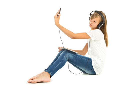 Young girl sitting on the floor taking a selfie with headphones