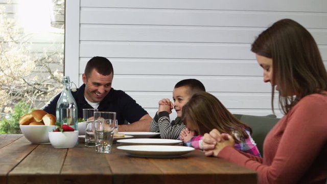Family praying before eating meal outside on patio