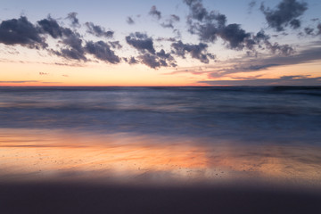 Beautiful sunset at the beach after a summers day, reflections in the water