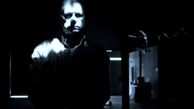 A mysterious strobe of light reveals a ghostly male figure standing in the shadows.