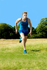 Young fitness man running on grass