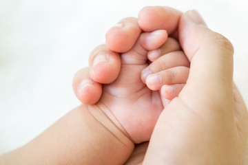 Mather hand holding baby hand on white background.