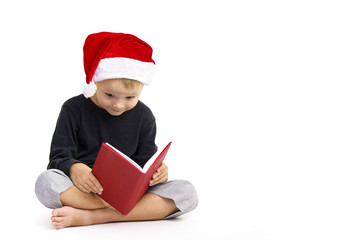 boy in a hat of Santa Claus reading a book