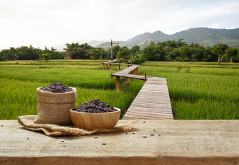 Naklejka premium Rice berry in bowl and burlap sack on wooden table with the rice