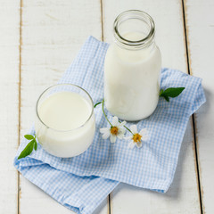 A bottle of milk and glass with Napery of milk on a white wooden