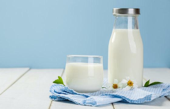 A bottle of rustic milk and glass of milk  with Napery on a whit