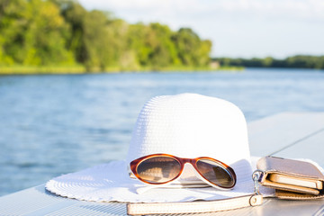 vacation and technology accessories on lakeside smartphone,  hat