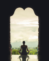 Silhouette young woman practicing yoga on the temple at sunset -