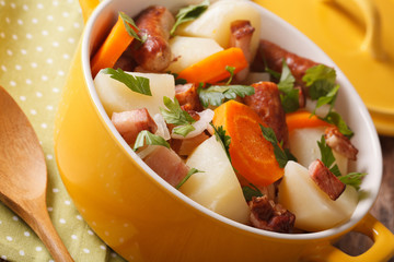 Irish cuisine: tasty coddle with pork sausages, bacon and vegetables macro. horizontal
