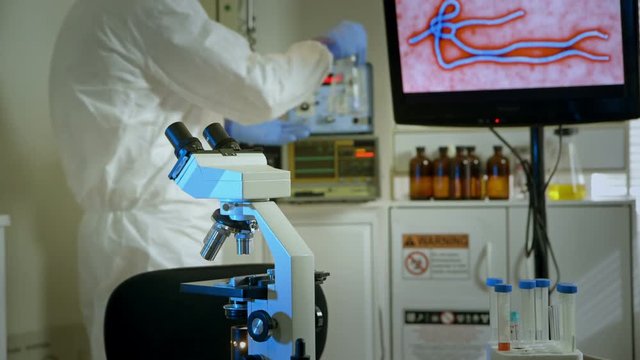 virologist walks to desk with a flask to study