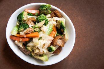 Crispy pork stir-fried with Broccoli and Carrot in Thai style isolated on brown background