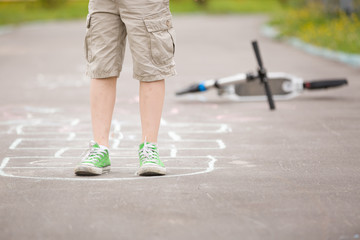 Closeup of boy's legs and hopscotch drawn on asphalt. Child playing hopscotch on playground outdoors on a sunny day. outdoor activities for children.