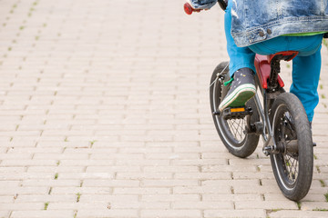 Back view on a kid boy riding on a small bicycle in the park. Child on the bike on asphalt road. Children activities outdoors.