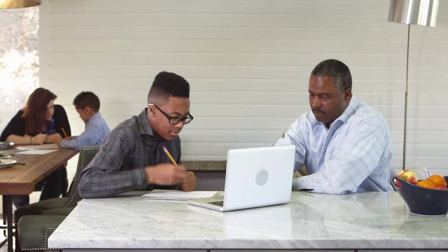 African american teenager using laptop with father helping