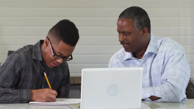 African American father tutoring son in homework