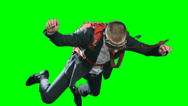 Businessman escaping crisis in business literally jumping off with parachute, shot of man in formalwear and aviator goggles flying in mid air, chroma key against green screen background