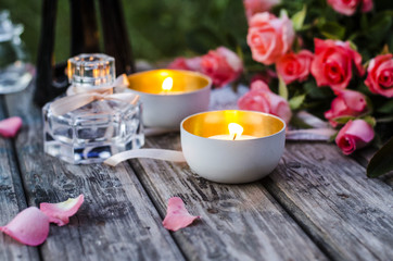 Romantic evening. Burning candles, pink roses on a wooden table.