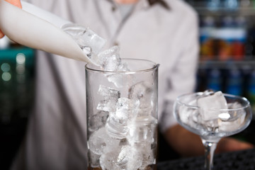 Barman's hands making ice for cocktail