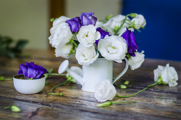 Floral background. Beautiful white and purple roses in a vase on a wooden table.