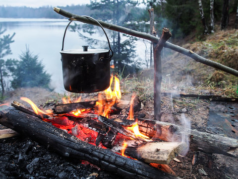 Cooking on the fire for a camping trip. Pot over a fire outdoors. The romance of the wild tourism and food in camp. Backpacking on the nature at sunset.