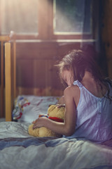 distraught little girl cuddles a teddy bear