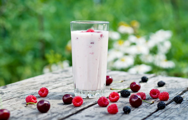 Ripe raspberries and cherries on a wooden table in the garden