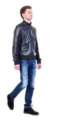Back view of going handsome man. walking young guy. Curly guy in a black leather jacket is proudly raising his head.