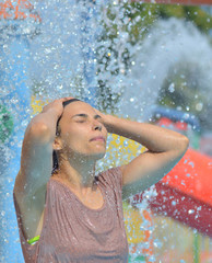 Obraz premium Beautiful woman enjoying under a water jet with thousands of drops in the background