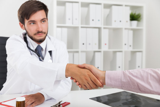 Serious doctor shaking hands with patient