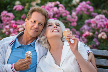 Fototapeta premium Man smiles and hugs woman. Couple with ice cream. Let's have a rest together. Every moment is priceless.