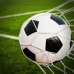 Plakat Soccer football in Goal net with green grass field.