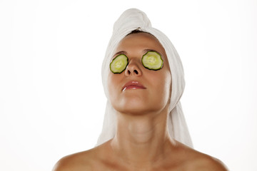 young woman with a towel on her head and cucumbers on her eyes