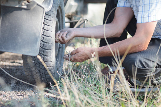 Man repairing punctured wheel in wild forest (focus on hand)