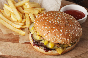Burger (hamburger) with french fries and sauce. Wooden background.