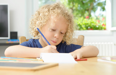 little blond boy drawing in his home