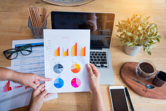 Top view of young working woman using laptop and reading report , graphs , charts, document at work. Business woman working at her desk.