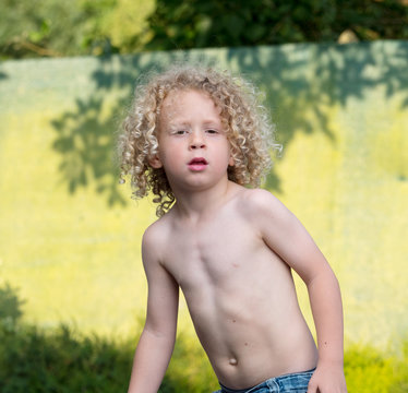 little boy shirtless playing in the garden