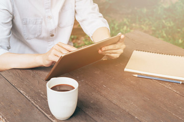 Hand woman using tablet on table in garden at coffee shop with v
