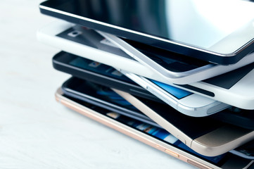 Stack of high-end smartphones on white wooden desk