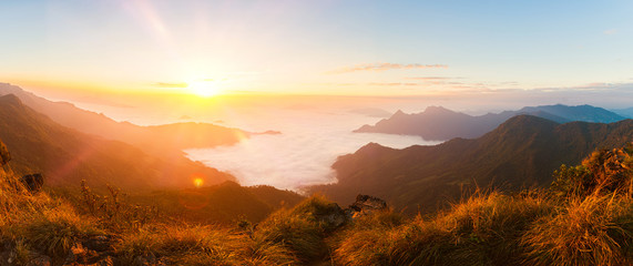 Fototapeta na wymiar Panorama of beautiful sunrise in the mountains with white fog between peaks. Banner. Selective focus.