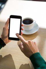 Hand using mobile phone with cup of coffee in table