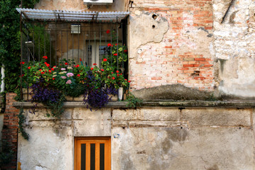 Fototapeta na wymiar Old picturesque balcony decorated with colorful flowers in Rijeka, Croaatia. Rijeka is selected as the European Capital of Culture for 2020.