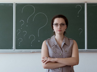 Young woman and question marks on the blackboard behind her