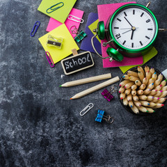 School stationery, pencil, pen, note, alarm clock on grunge chalkboard