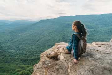 Woman resting on edge of cliff